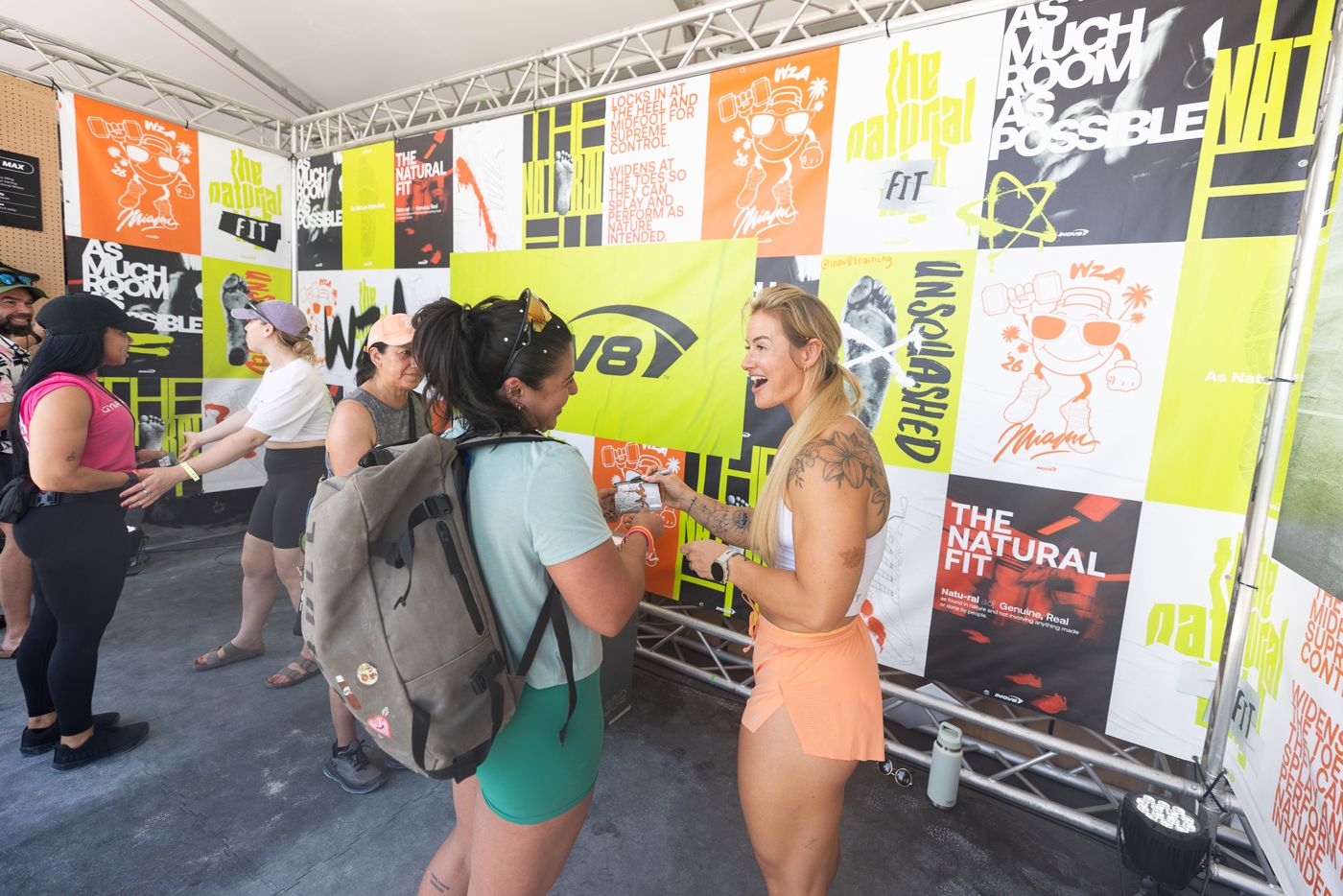 Fans meeting athletes at the INOV8 truss booth with a poster-collage wall