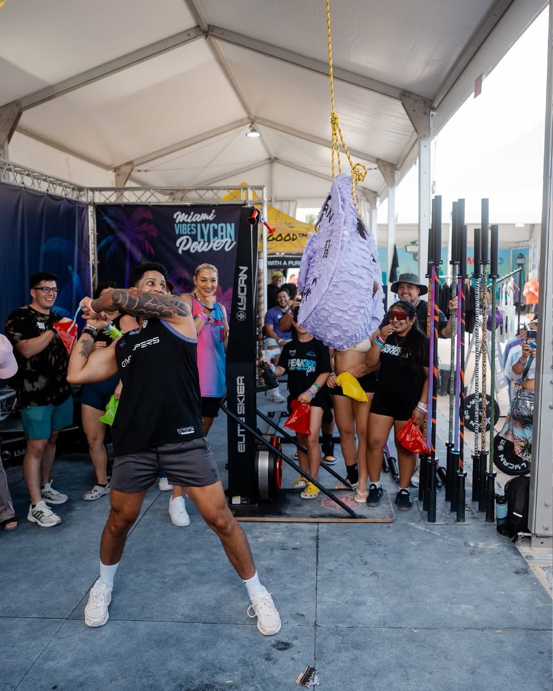 The Lycan Fitness booth with a barbell wall, a piñata and a crowd