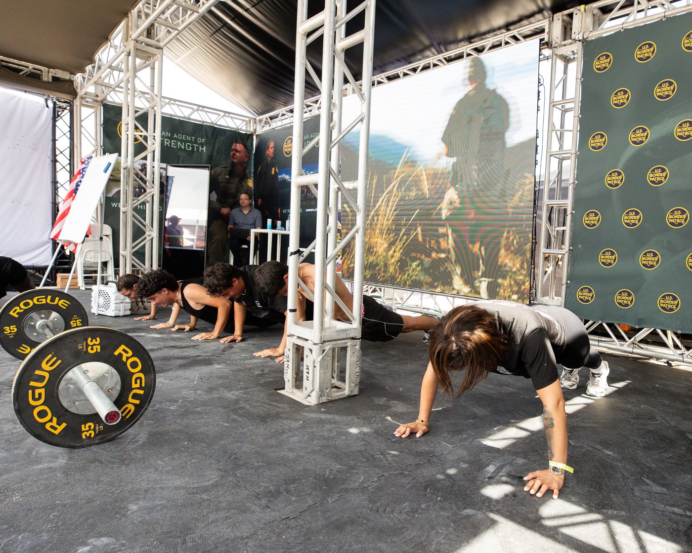 U.S. Border Patrol booth with a video wall, branded backdrop and a burpee challenge