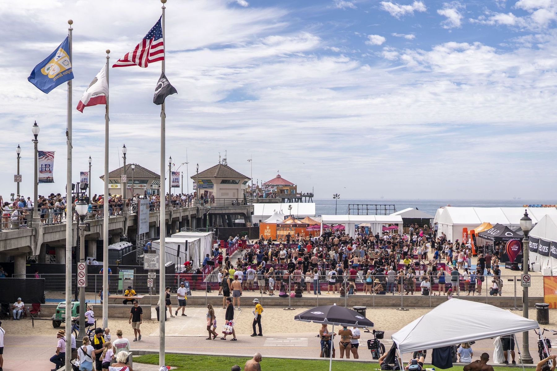 American, state and city flags flying above a crowd at a public event