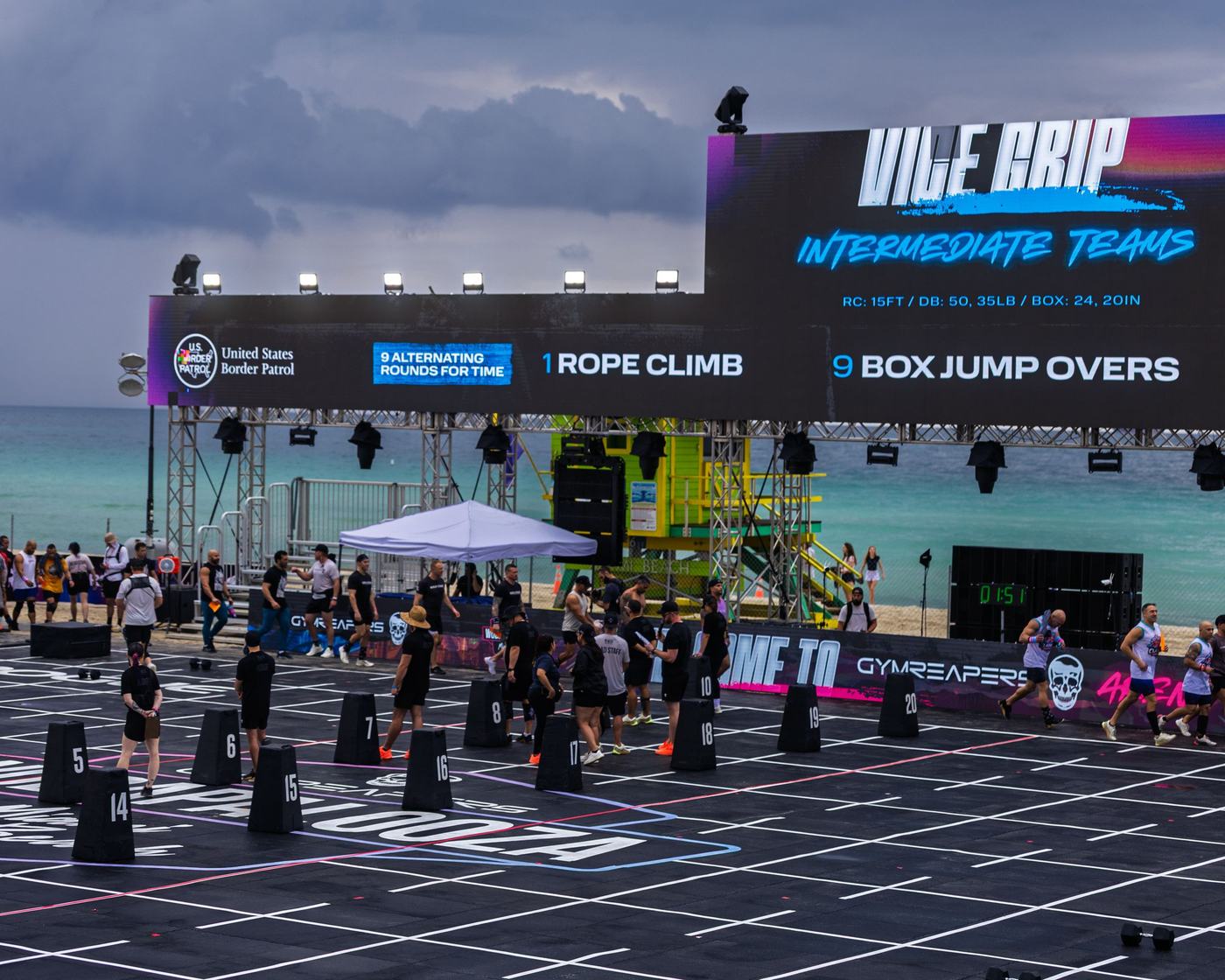 Athletes on the beach competition floor under a big event scoreboard